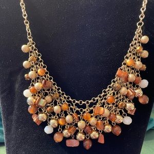 Gold bib netting necklace with gold, brown, and white bead dangles. 17 inches